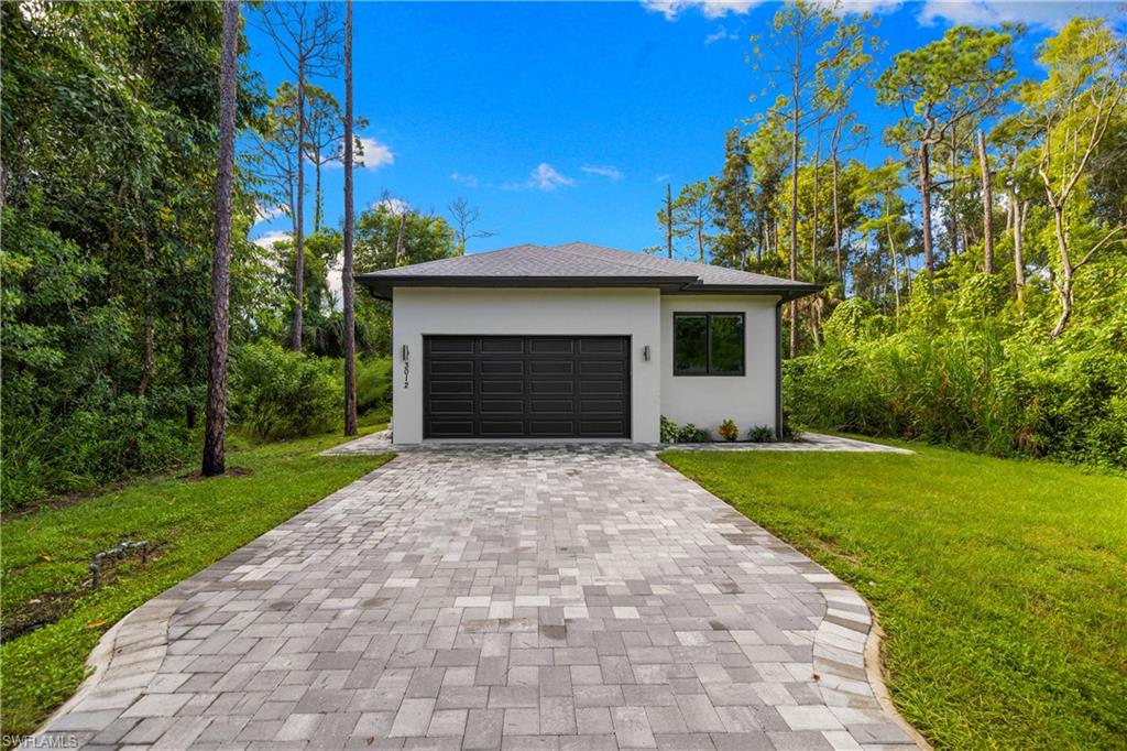 Contemporary single-story exterior featuring a dark gray shingle roof, white stucco facade, and an integrated two-car garage with a dark panel door