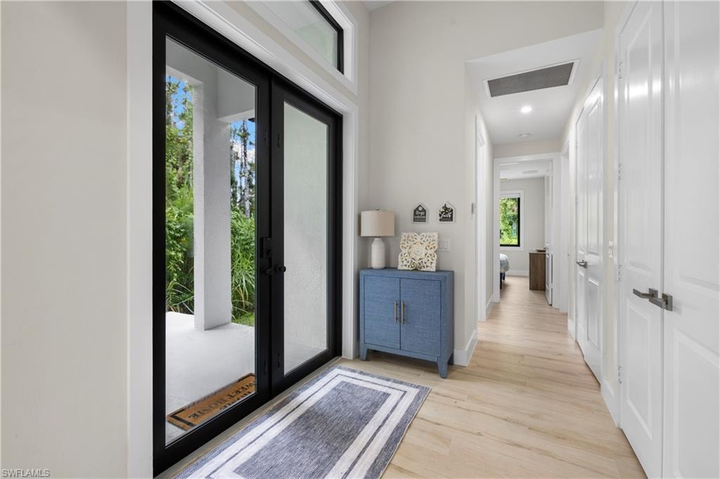 Entryway featuring double glass-panel doors with black frames, transom window, recessed lighting, and wood-finish flooring
