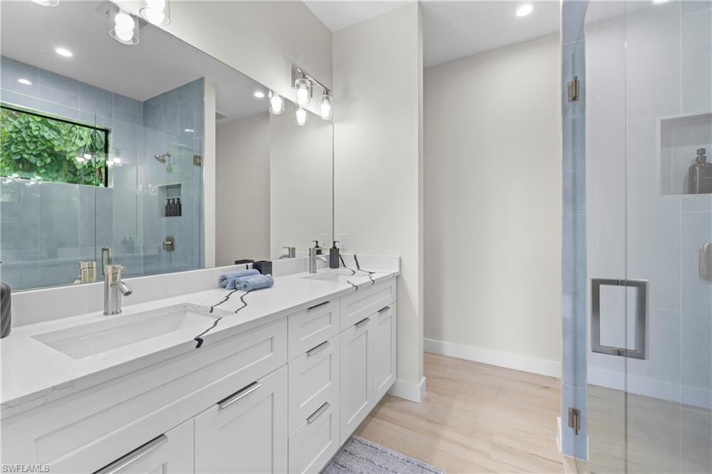 Modern bathroom featuring a dual vanity with white cabinetry, integrated sinks, and a stone-finish countertop