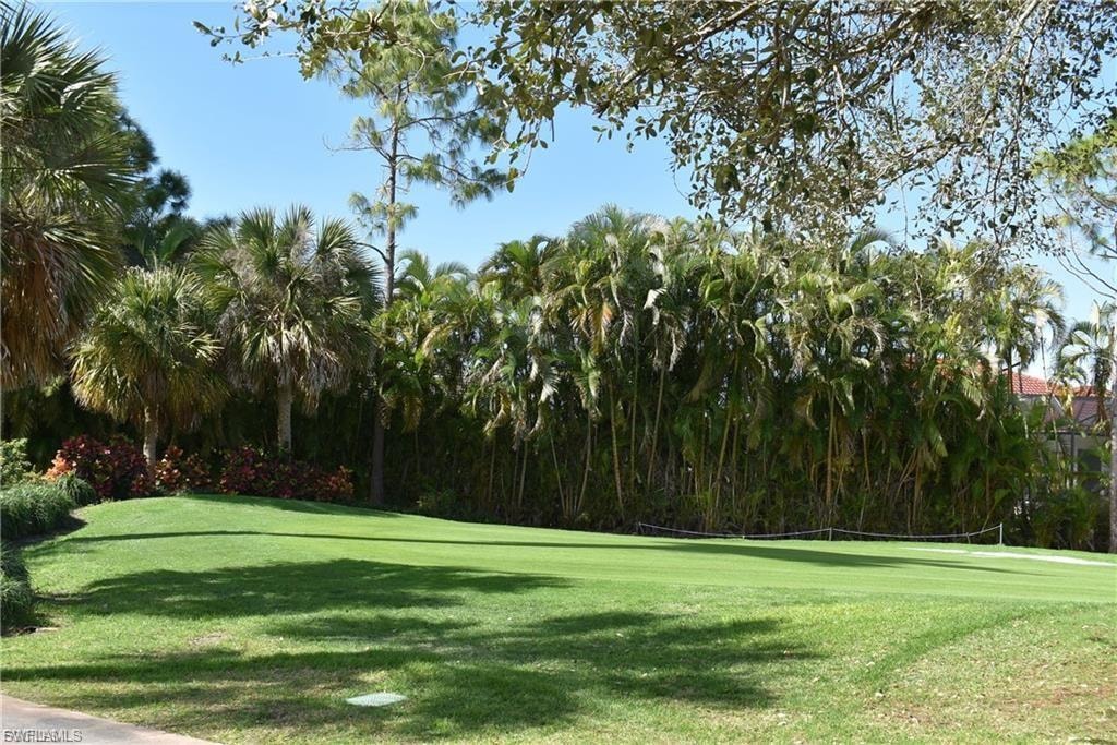 View of community with view of golf course and a lawn