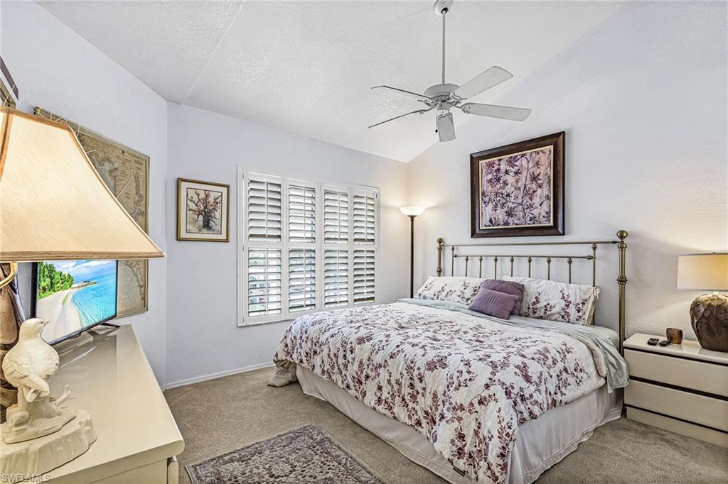 Carpeted bedroom with vaulted ceiling, a ceiling fan, and a textured ceiling