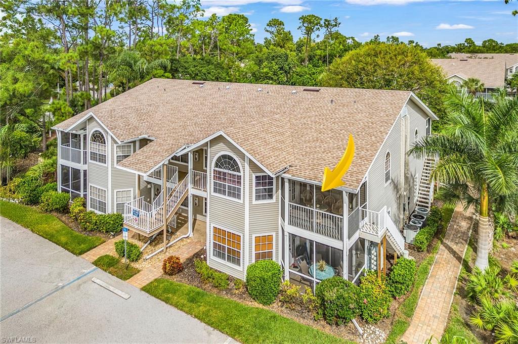 Back of house with stairs, roof with shingles, a sunroom, and view of wooded area