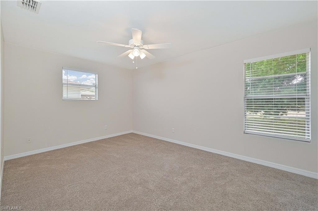Spacious interior room featuring light-toned carpeting and neutral wall finishes