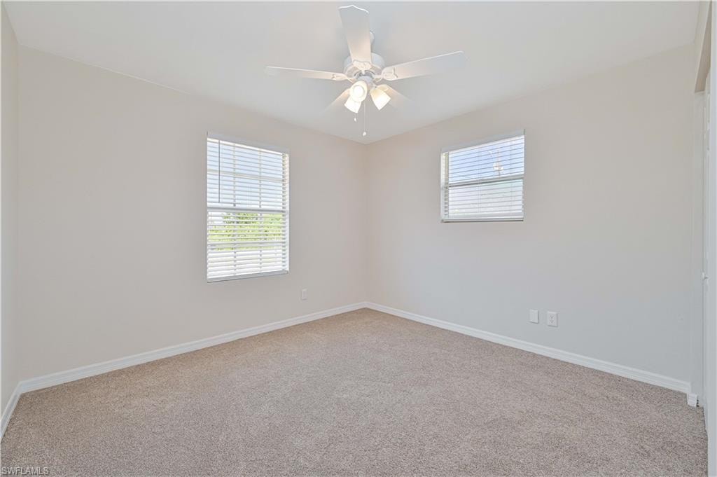 Spacious room featuring neutral wall tones and a textured carpet