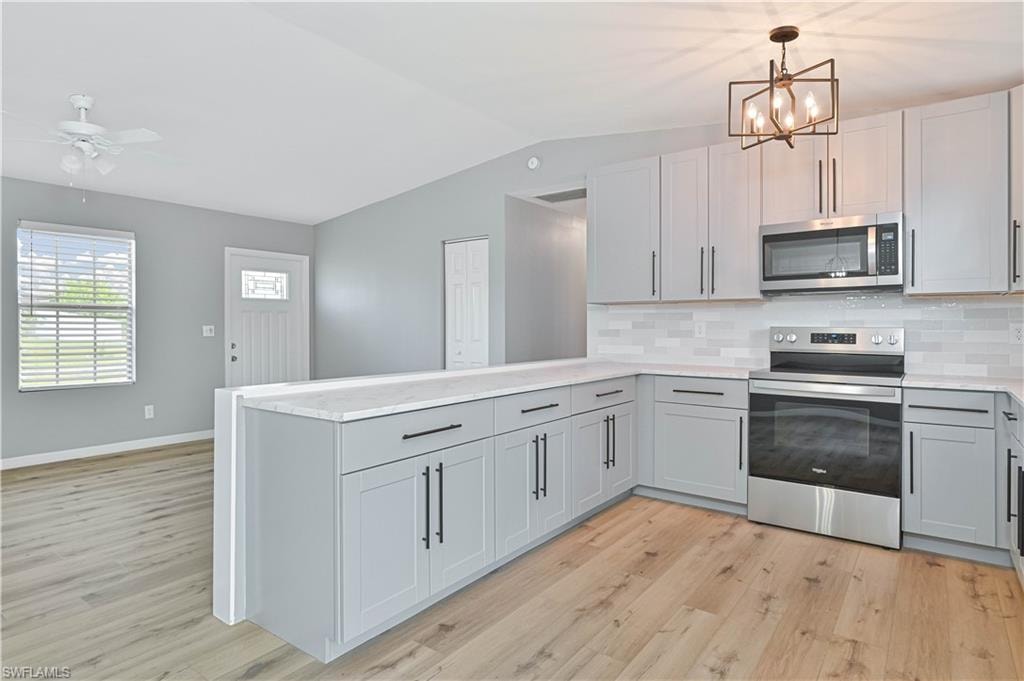 Modern kitchen featuring light gray cabinetry, stainless steel appliances, white subway tile backsplash, and light wood-finish flooring