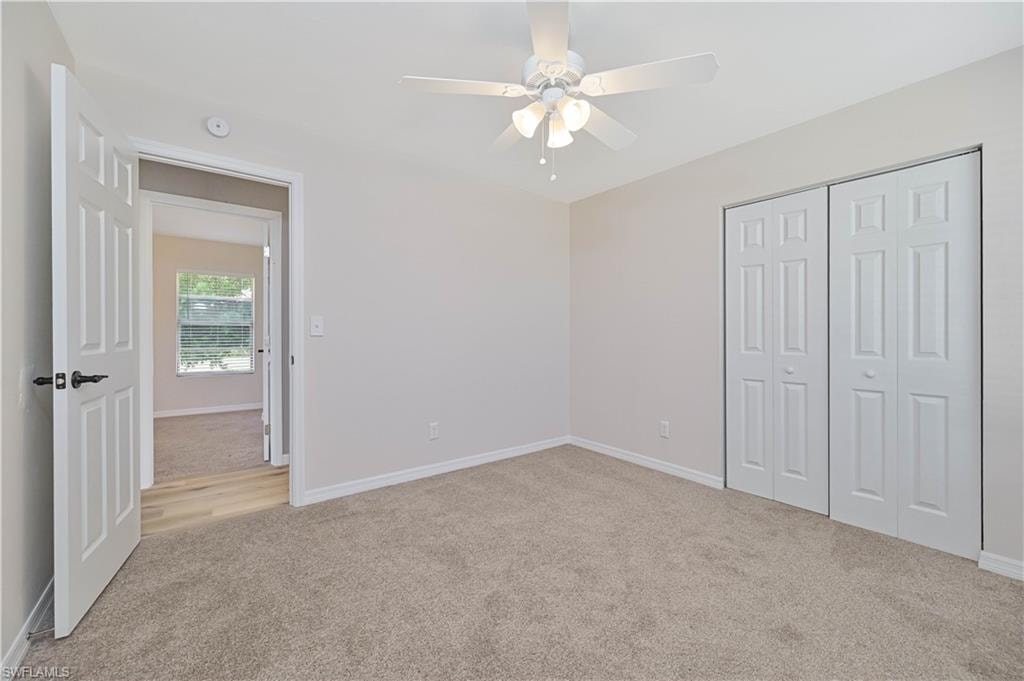 Neutral-toned carpeted interior space with a ceiling fan with integrated lighting