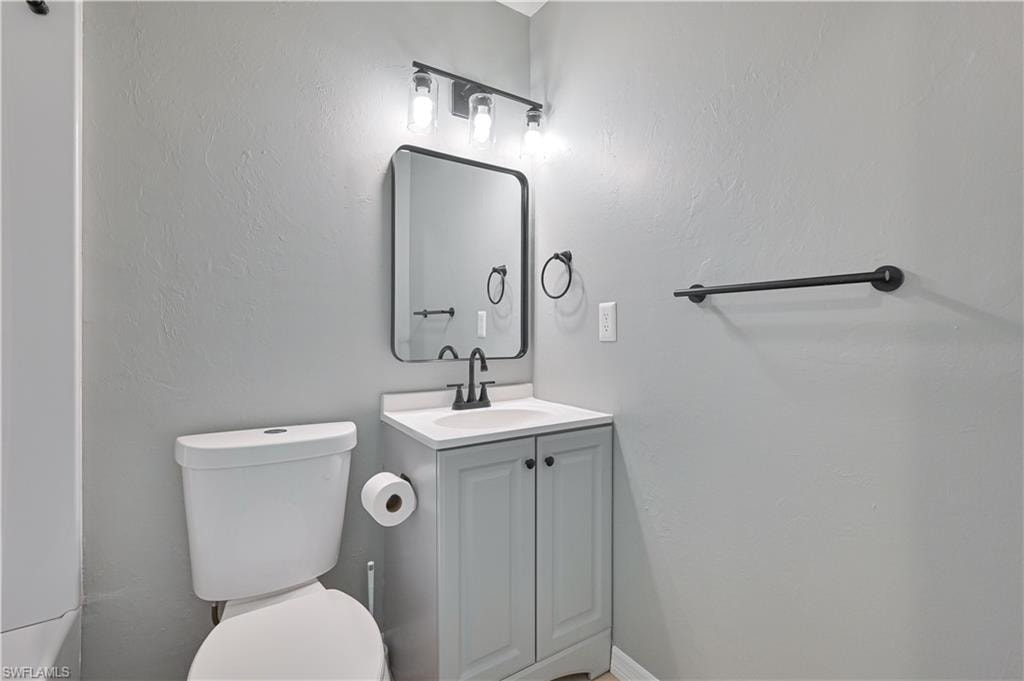 Contemporary vanity with a white countertop, matte black hardware, and an illuminated mirror