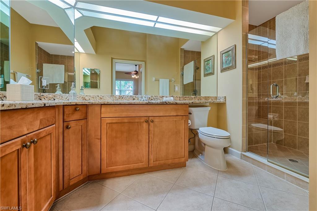 Bathroom with light tile patterned floors, a stall shower, vanity, and a ceiling fan