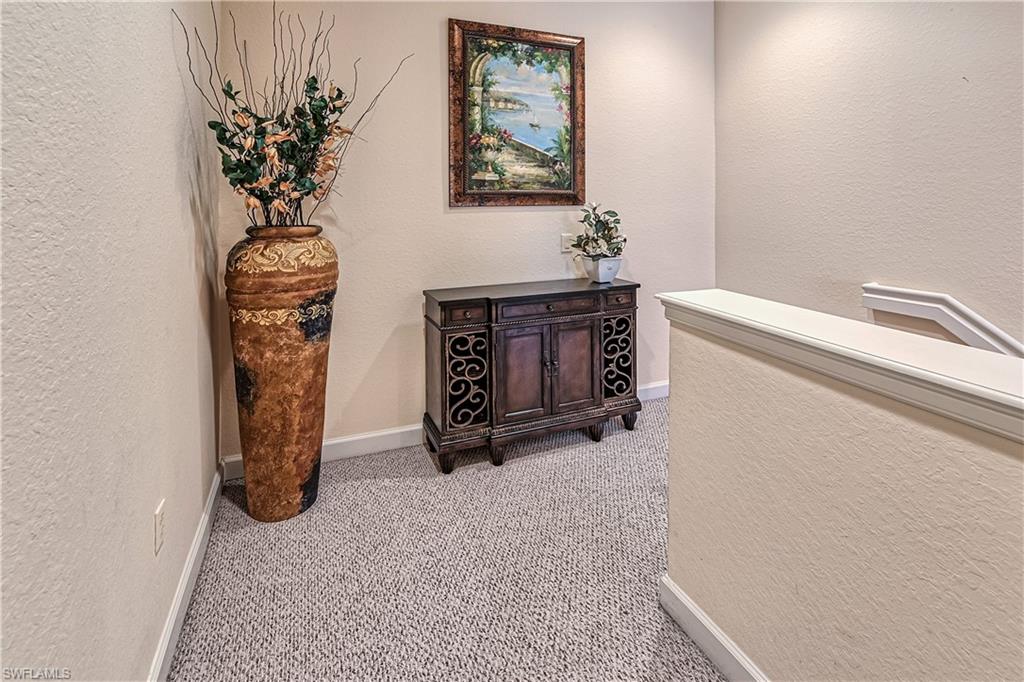 Hallway featuring a textured wall and carpet flooring