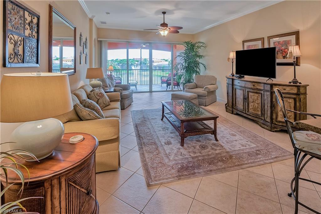 Living room featuring light tile patterned floors, crown molding, and ceiling fan