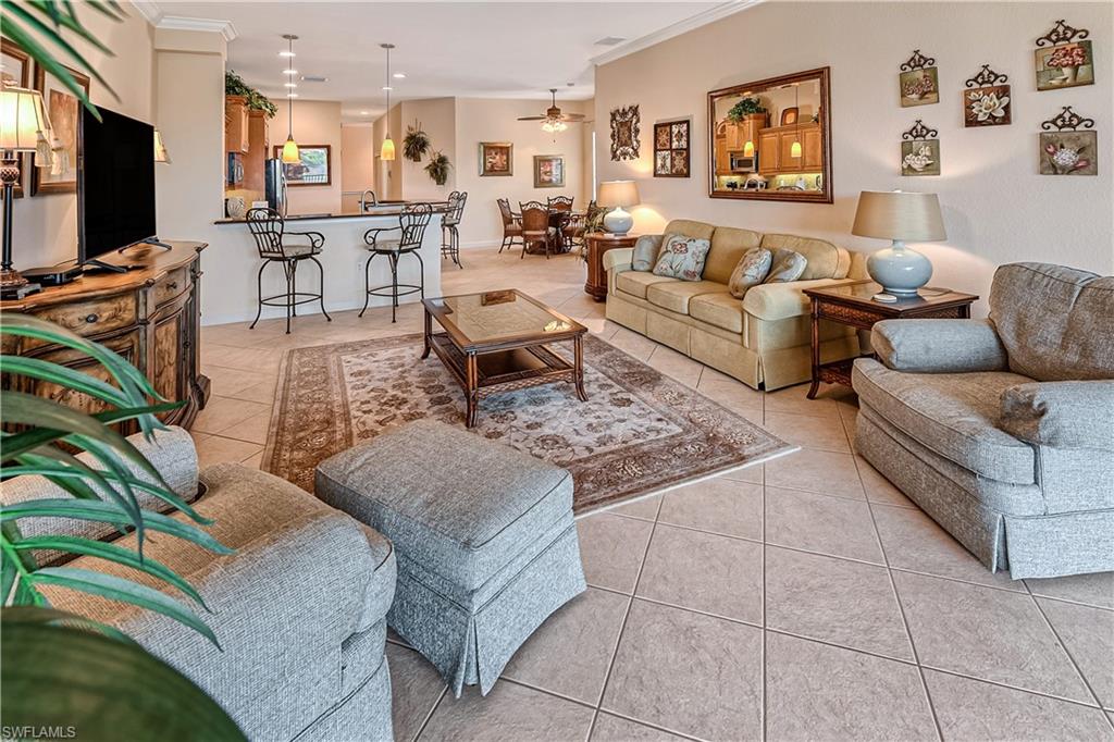 Living room with light tile patterned floors, a ceiling fan, and crown molding