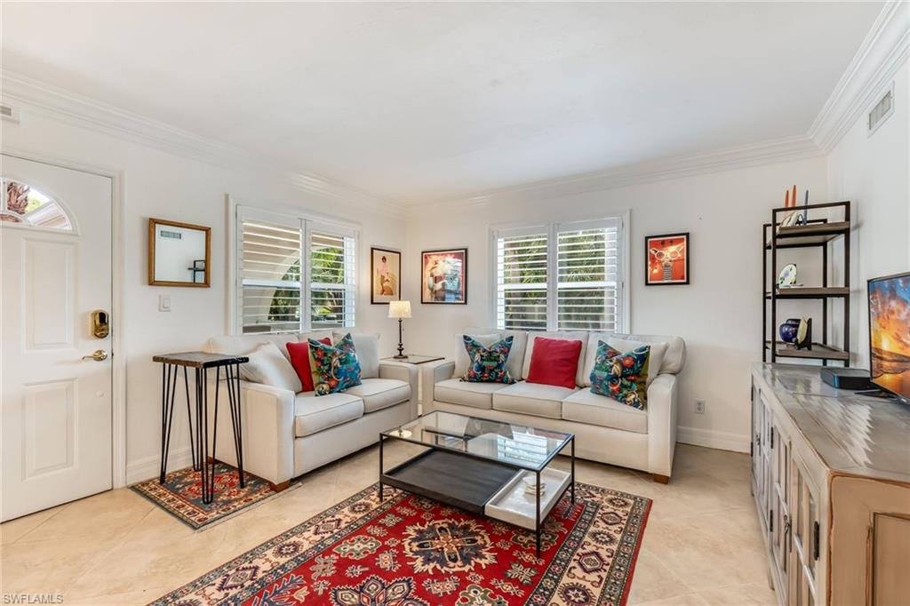 Tiled living room featuring ornamental molding and a wealth of natural light
