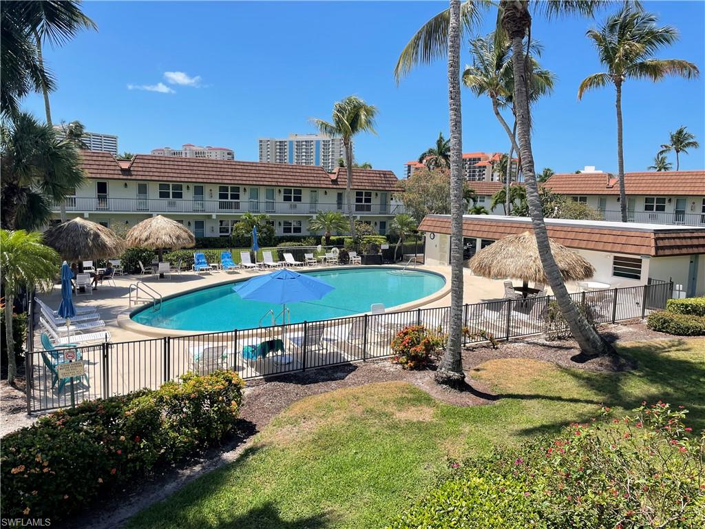 Outdoor swimming pool area featuring a freeform pool, surrounding lounge seating, and two tiki-style cabanas