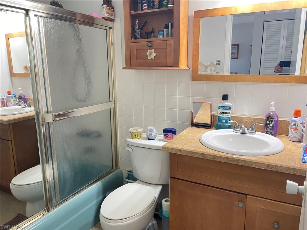 Bathroom featuring a light wood-finish vanity with a built-in sink, a framed mirror, and a wall-mounted wooden cabinet