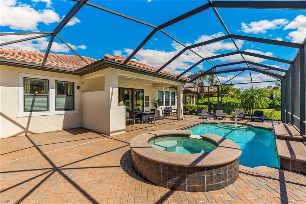 Screened enclosure featuring a swimming pool, integrated spa, and extensive paver patio