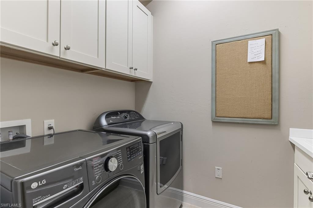 Laundry area featuring white cabinetry with silver hardware, neutral wall paint, light-colored baseboards, and a partial countertop with an integrated sink