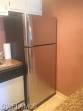 Kitchen featuring freestanding refrigerator, white cabinetry, light countertops, and baseboards