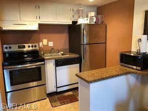 Kitchen with stainless steel appliances, ventilation hood, white cabinets, a peninsula, and a sink