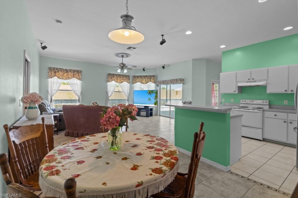 Open-concept living space featuring a breakfast bar, white cabinetry, and a tile floor