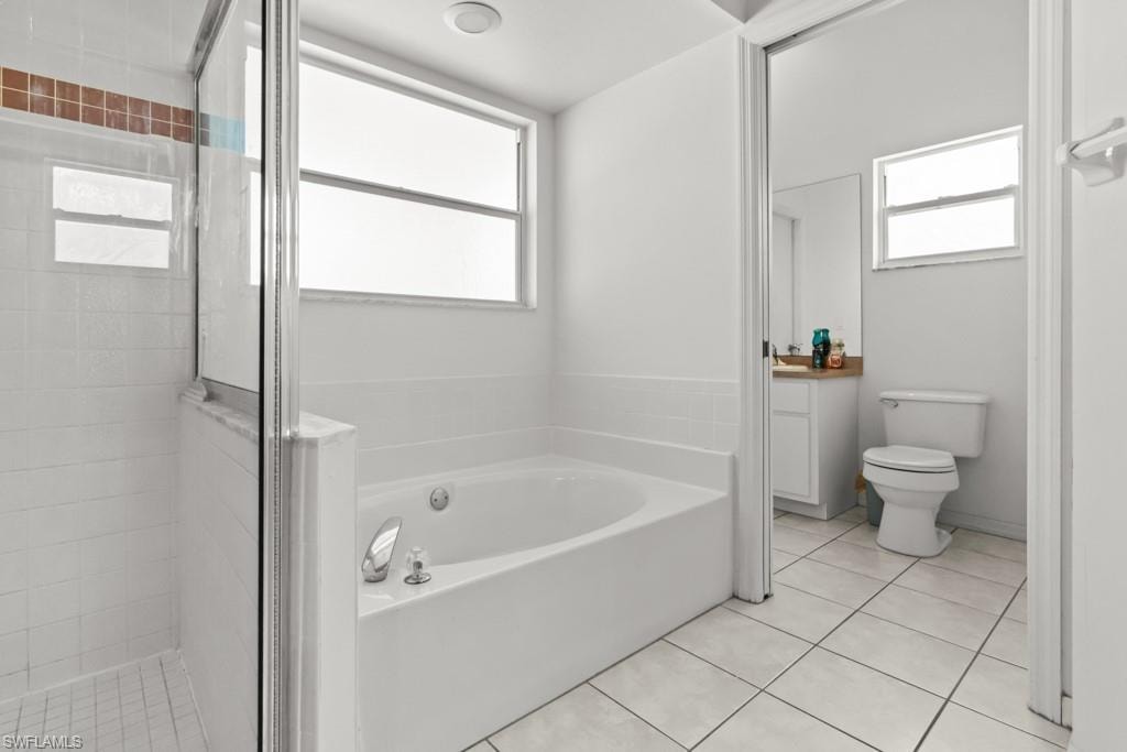 Bathroom featuring a built-in tub, separate glass-enclosed shower, dual privacy windows, and white tile flooring