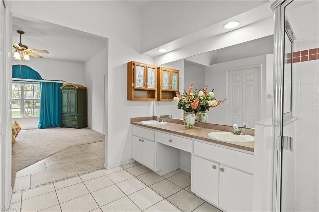 Dual vanity with white cabinetry, brown countertops, and an expansive mirror