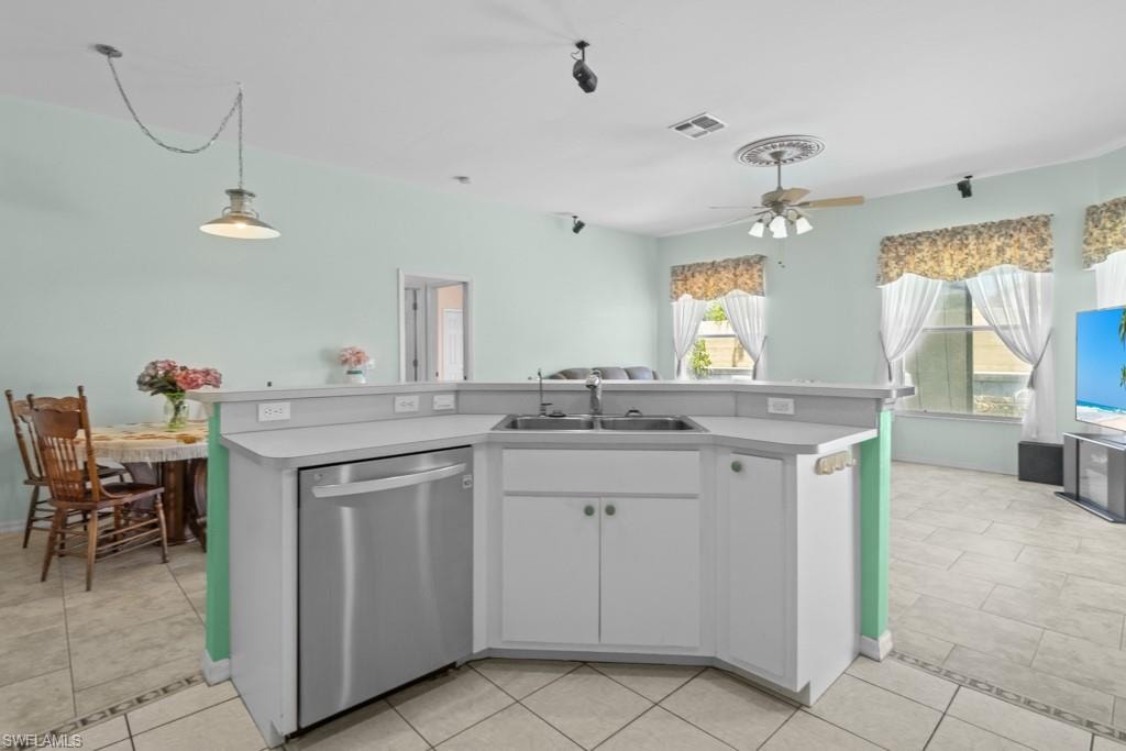 Kitchen island featuring a double basin sink, stainless steel dishwasher, and white cabinetry