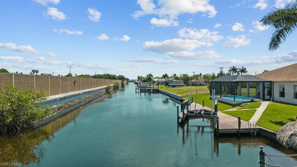 Waterfront property featuring a private boat dock, screened pool enclosure, paved pool deck, and manicured green lawn