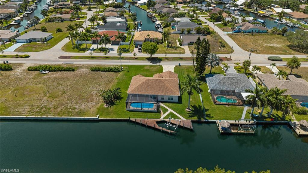 Waterfront property featuring a screened-in pool, private dock structure, and lush green lawn