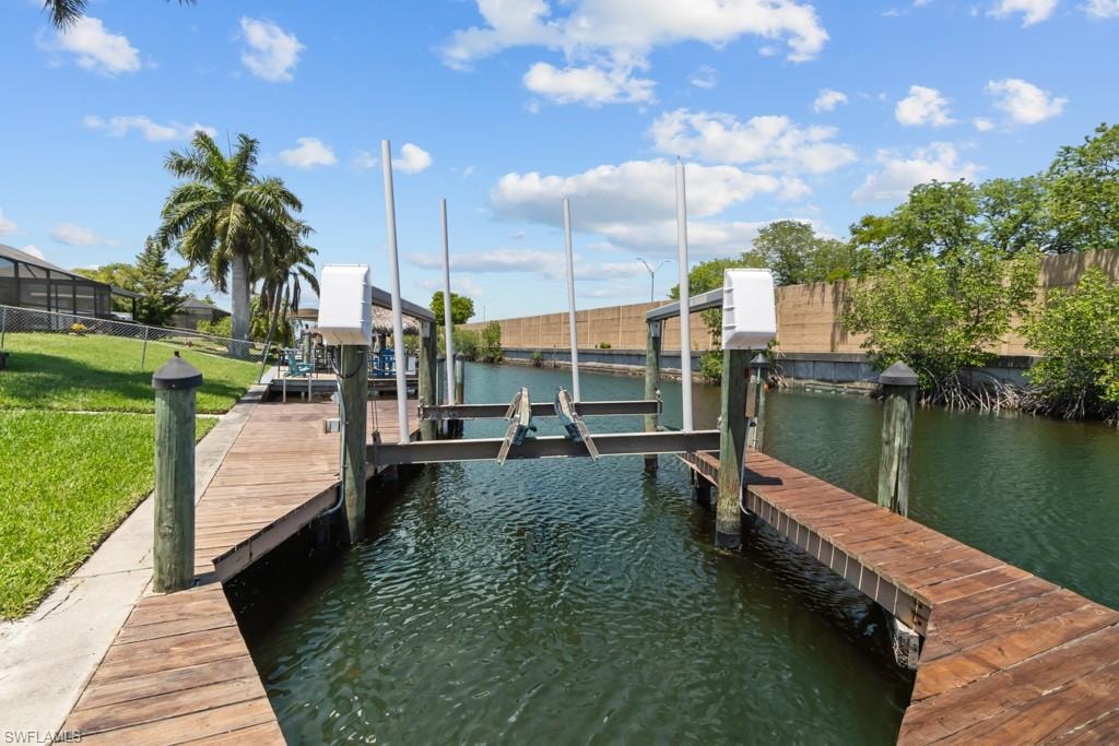 Waterfront property featuring a private boat dock with a lift system, direct water access, and mature palm trees