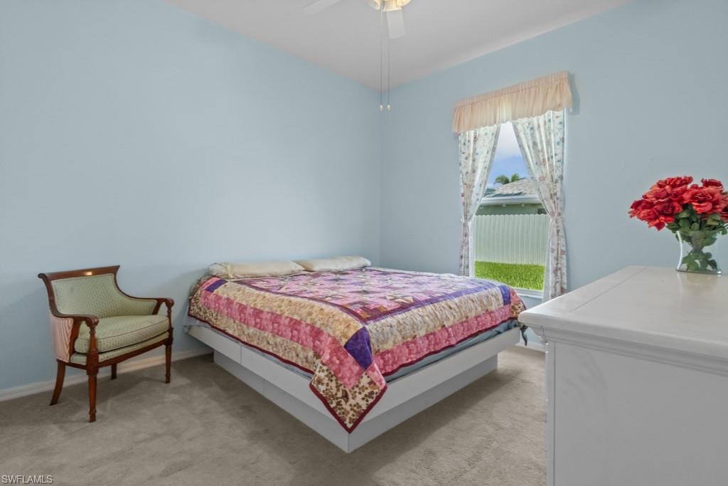 Carpeted room with light blue walls, featuring a window with a white valance and floral curtains