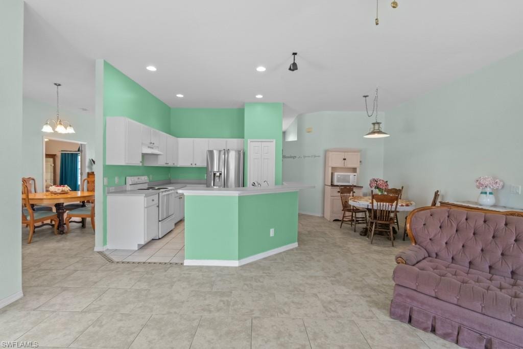 Open-concept living area featuring light-toned flooring, a kitchen with white cabinetry, a breakfast bar, and stainless steel appliances