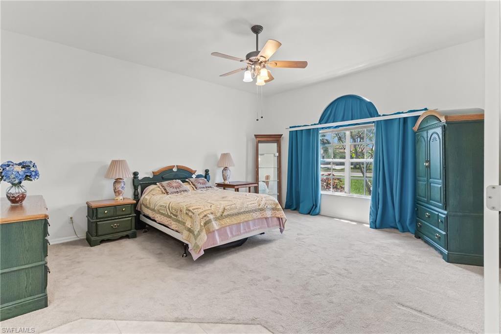 Spacious room featuring vaulted ceilings, light-colored carpeting, and a large arched window