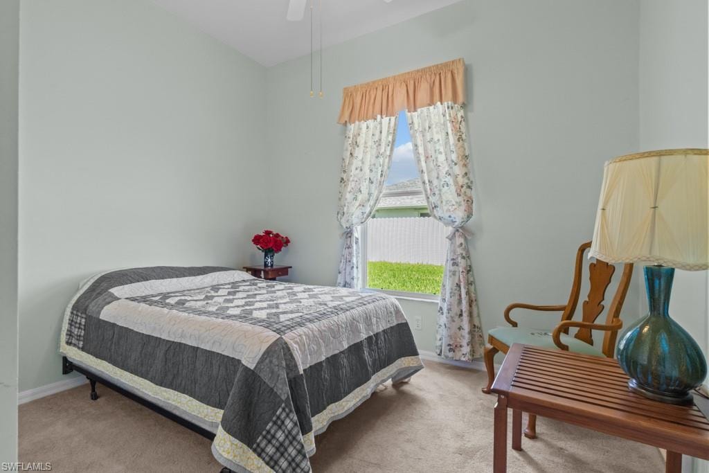 Carpeted room with a ceiling fan, light-colored walls, and a window with a valance and drapes