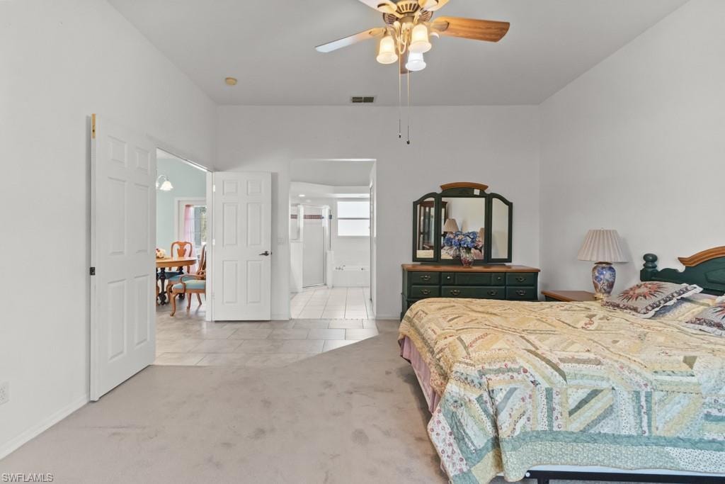 Carpeted bedroom featuring a ceiling fan with integrated lighting, white paneled doors, and an open doorway revealing a tiled area
