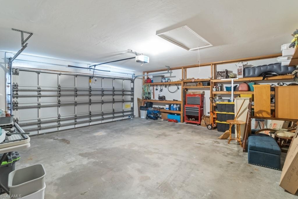 Spacious two-car garage with concrete flooring, overhead lighting, and built-in wood shelving for organized storage