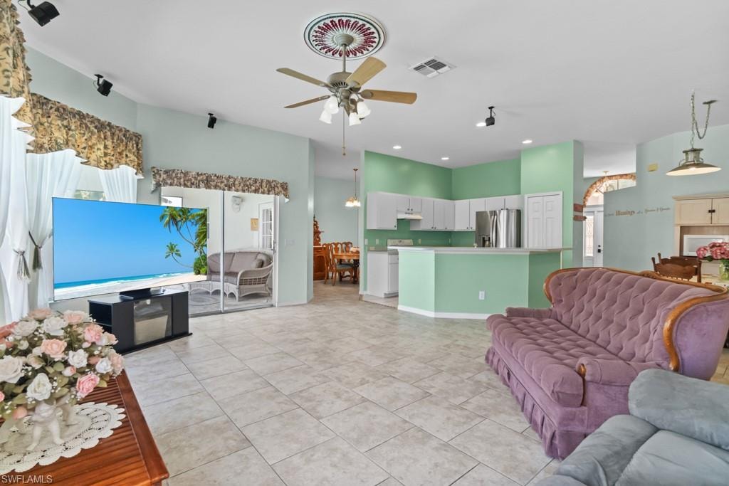 Open-concept living space featuring light-toned tile flooring, a ceiling fan with an ornate medallion, and recessed lighting