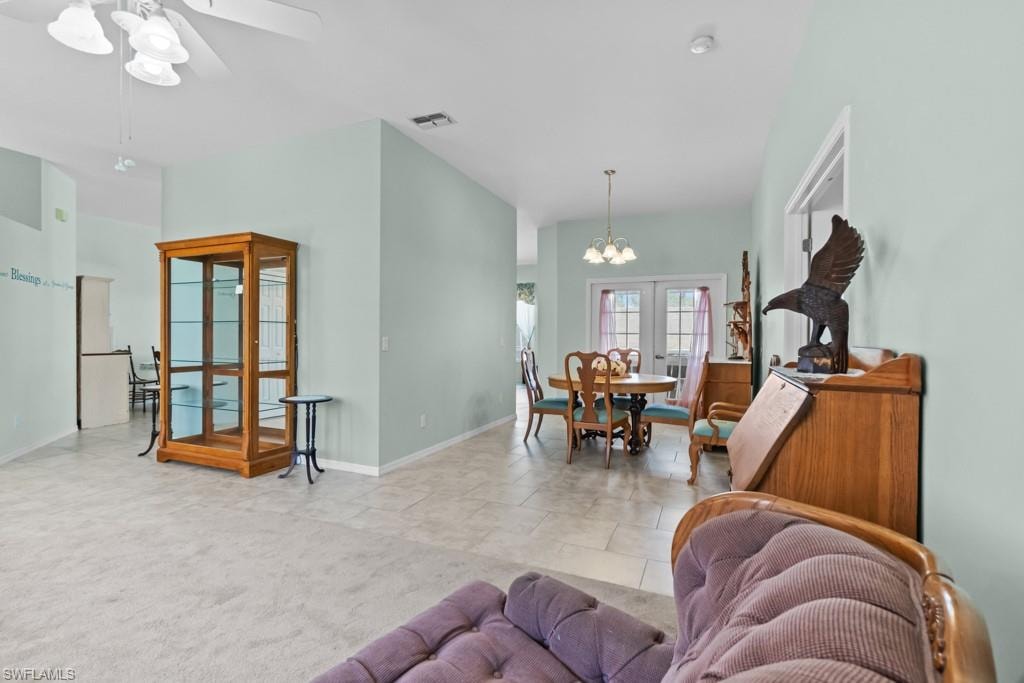 Spacious interior featuring a combination of carpet and tile flooring, vaulted ceilings, and light-toned walls