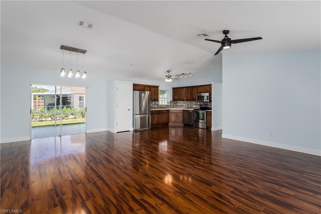 Open-concept living space featuring wood-finish flooring, a contemporary ceiling fan, and a kitchen with wood cabinetry and stainless steel appliances