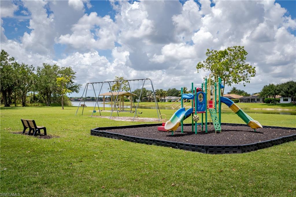 Playground featuring multiple slides and climbing elements, set on a dark protective ground covering in the community