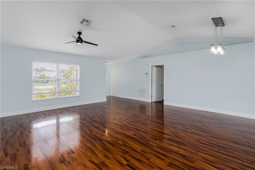 Spacious interior featuring wood-finish flooring, vaulted ceilings, a contemporary ceiling fan, and a modern multi-light pendant fixture