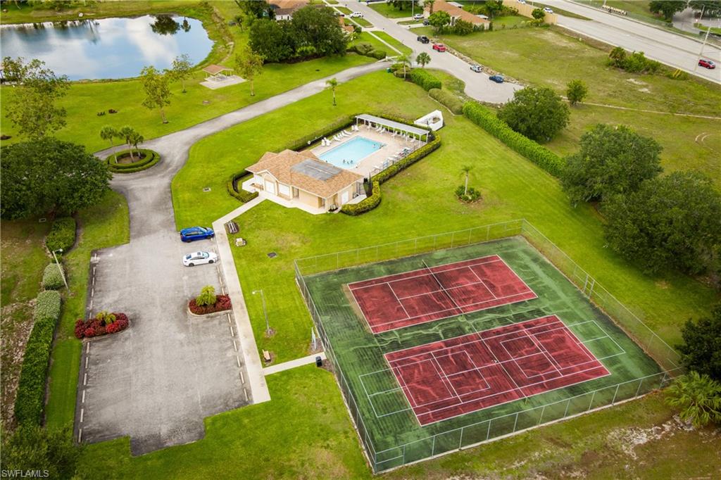 Community amenities featuring a clubhouse, swimming pool, two tennis courts, and a parking area, all surrounded by green spaces and a pond