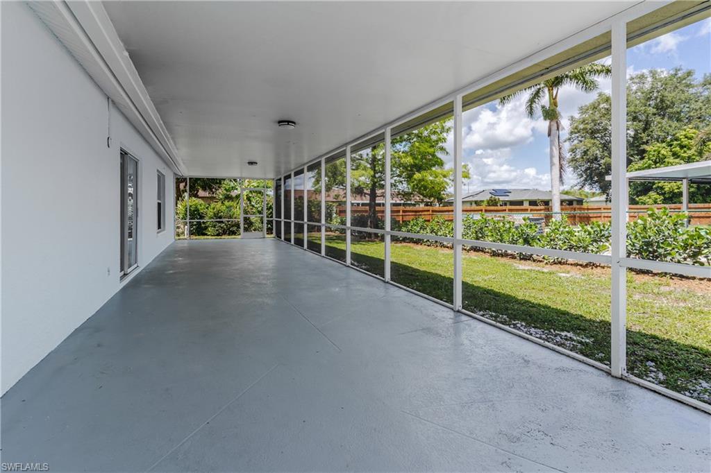 Expansive screened patio featuring a concrete floor, white walls, and a verdant lawn beyond