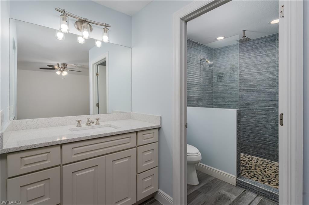 Bathroom featuring a single vanity with light grey cabinetry, a light speckled countertop, and a rectangular undermount sink