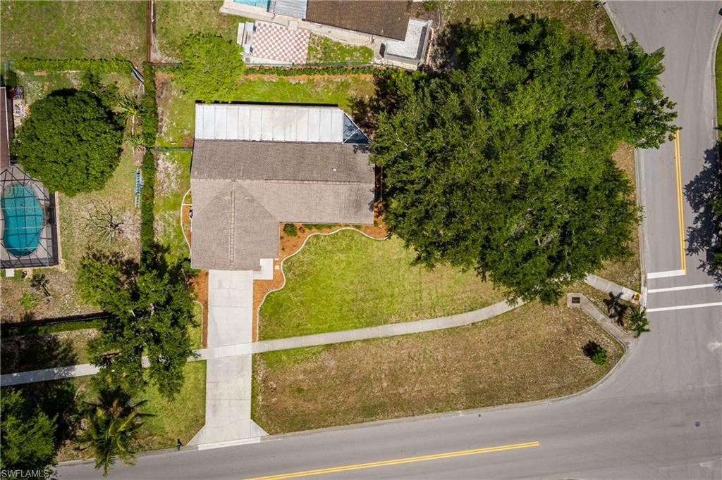 Gable roof residence with an attached carport, concrete driveway, and established front yard landscaping