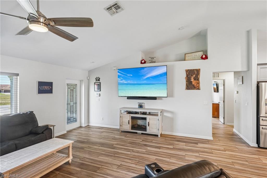 Bright living space featuring wood-finish flooring, vaulted ceilings, and a modern ceiling fan