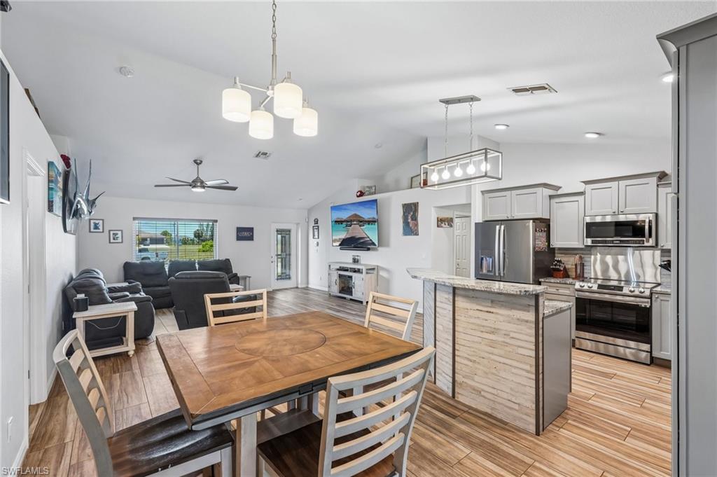 Vaulted ceilings define this open-concept living space, featuring wood-finish tile flooring throughout