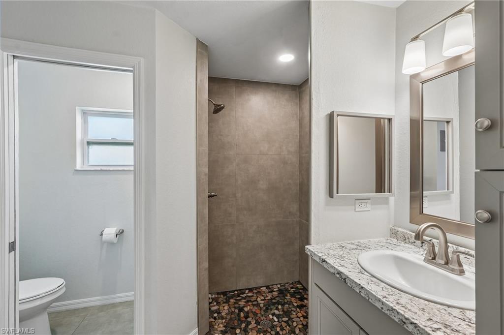 Bathroom featuring a walk-in shower with pebble flooring and large format wall tile