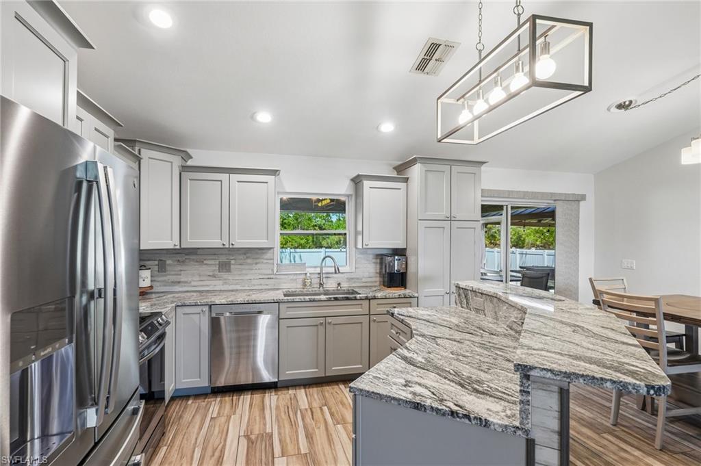 Modern kitchen featuring light gray cabinetry, stainless steel appliances, and wood-finish flooring