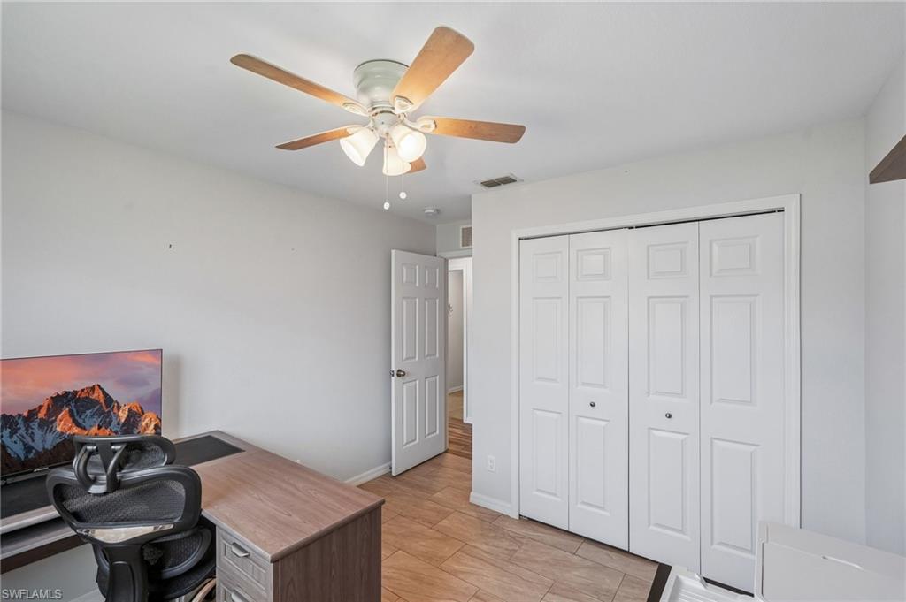 Bright room featuring a ceiling fan with integrated lighting, bi-fold closet doors, a paneled interior door, and tile flooring