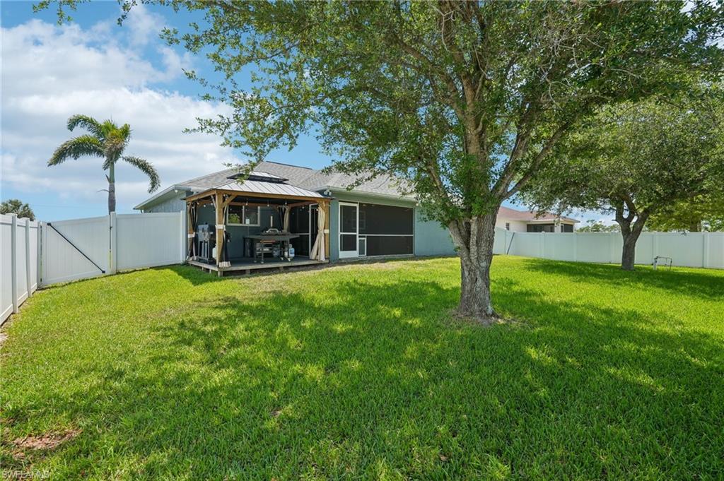 Expansive backyard featuring a manicured lawn, established trees, and a privacy fence
